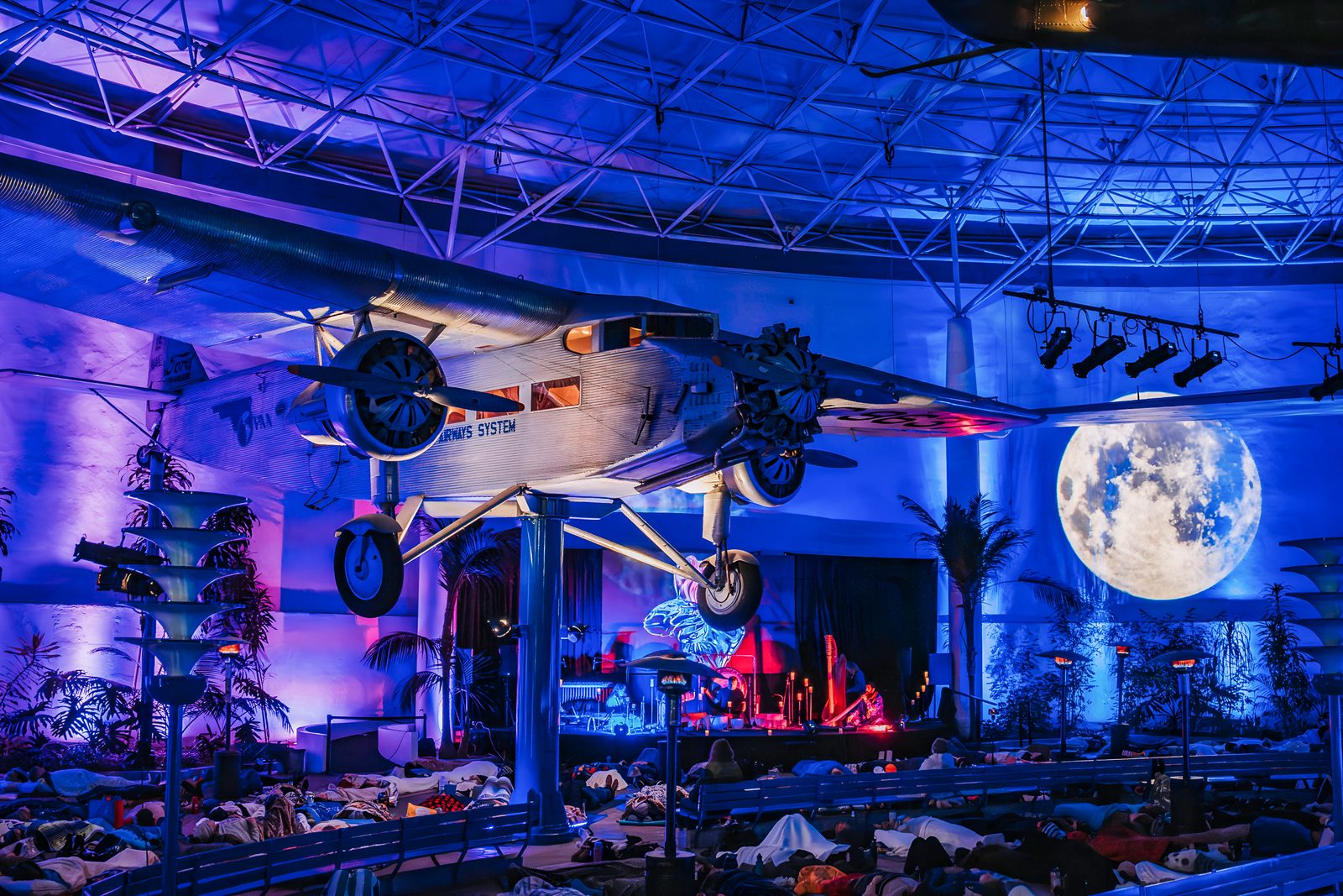 The Symphony beneath a vintage airplane and a giant moon at the San Diego Air & Space Museum