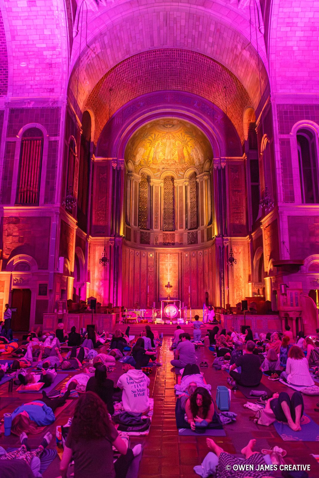Listeners on mats beneath a glowing golden apse