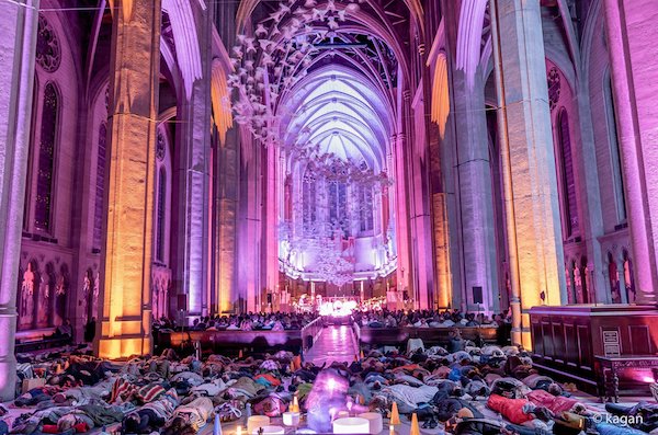 A full cathedral bathed in purple light during an evening sound bath