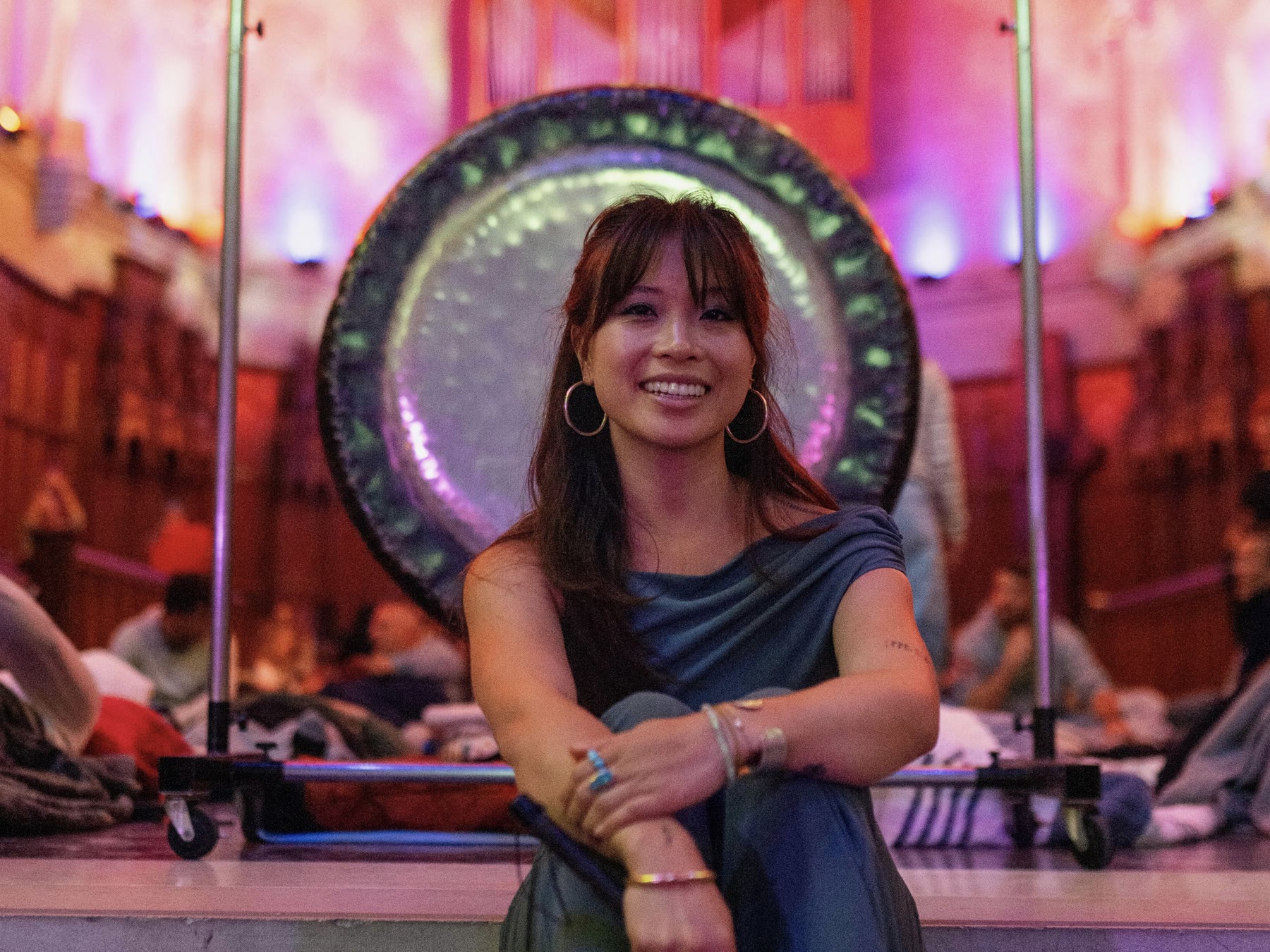 Sound bath practitioner seated in front of a large gong